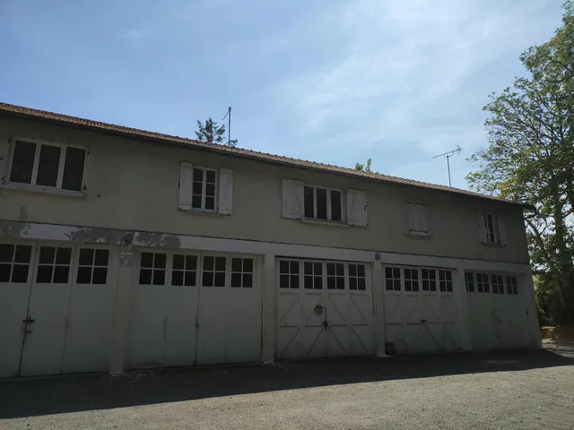 Le bâtiment à garages, haut, avec son toit en tuile peu pentu.