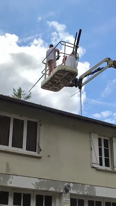 Nicolas Langlois dans le panier d'une nacelle pulvérise à la perche au-dessus d'un toit.