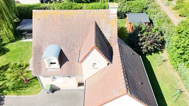Pavillon en tuile vu du ciel, lucarne cintrée en zinc et jardin arboré.