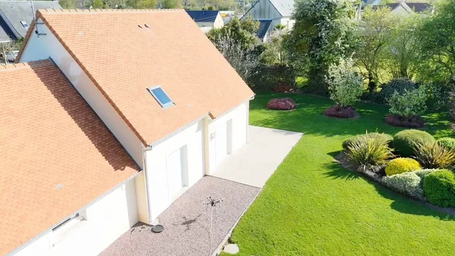 Vue au drone d'une maison à toiture en tuile orange, propre, au printemps, pelouse verte.