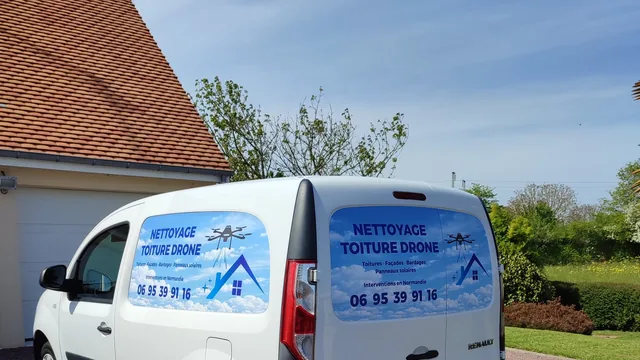 Le véhicule d'intervention floqué « Nettoyage toiture drone », garé devant une maison.